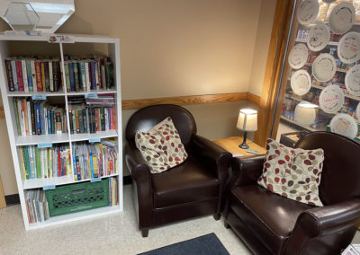The book corner at the community room, showing two comfortable chairs next to a bookshelf