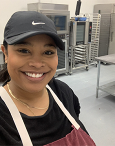 Christine Lugo-Yergenson, member of the Advisory Council, stands smiling in the food bank kitchen